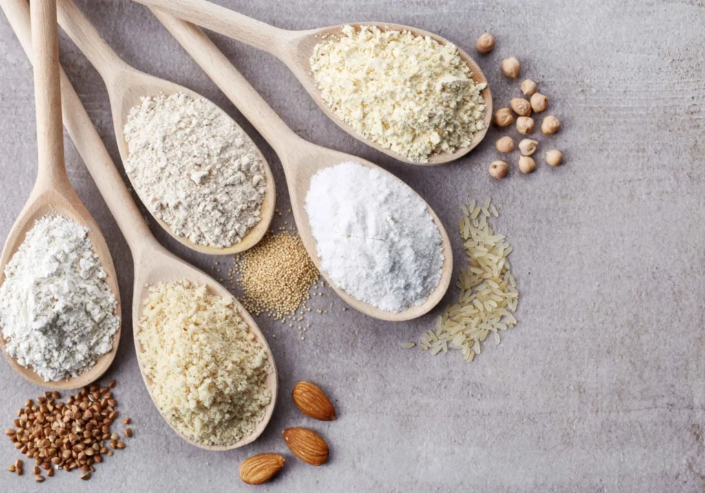 A table topped with wooden spoons filled with different types of food to show the possibilities of a gluten free baking mix.