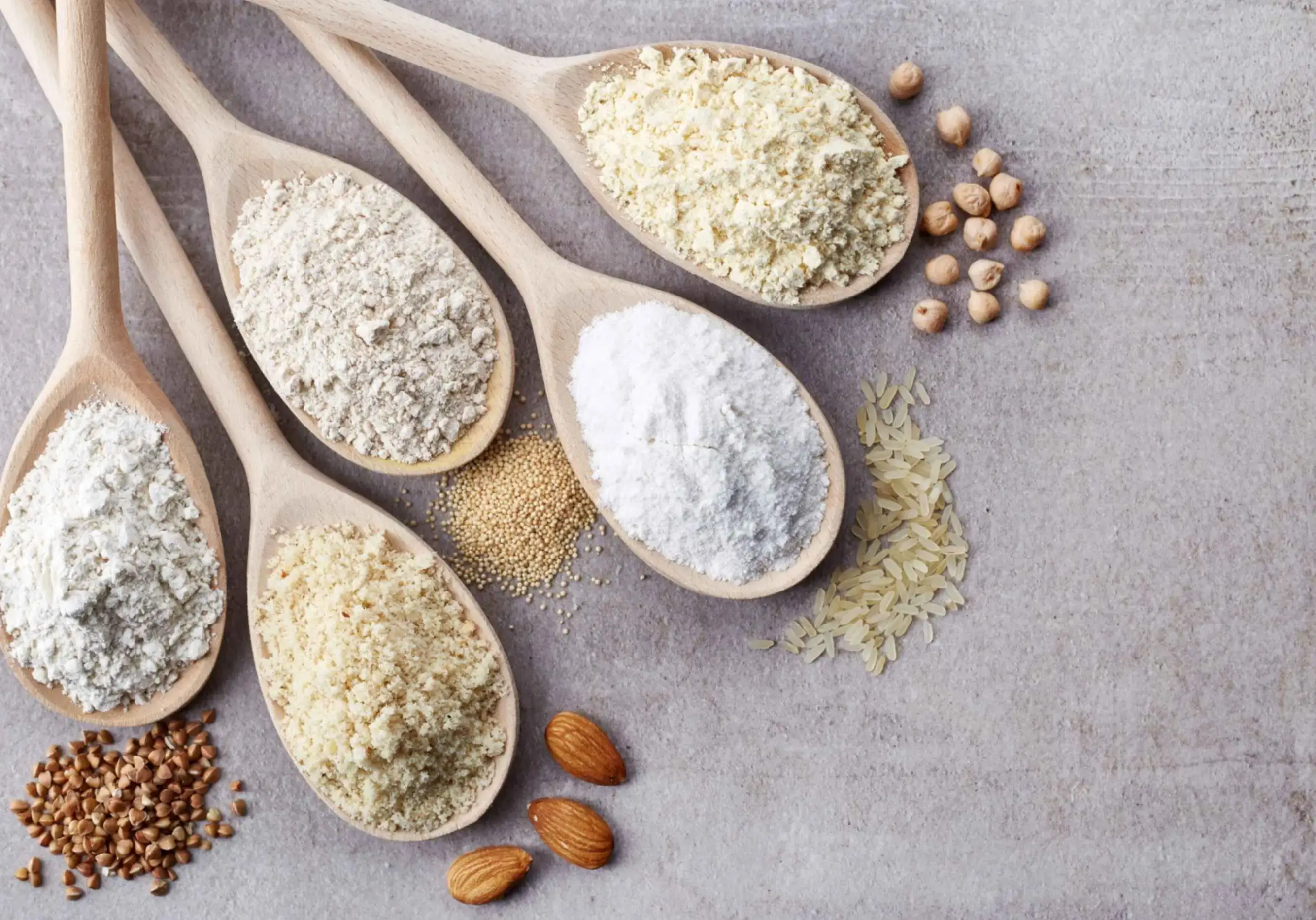 A table topped with wooden spoons filled with different types of food to show the possibilities of a gluten free baking mix.